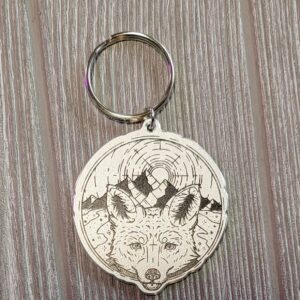 Round metal keychain with a drawing of a red fox/arctic fox hybrid on it